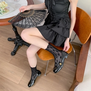 Detail of lace flower socks paired with black patent leather Mary Jane shoes