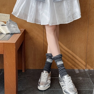 Detail showing ribbed knit fabric with lace edge and square embroidery tag on the socks