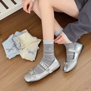 Detail of sweet bow socks with ruffled edges and heart embroidery worn with Mary Jane shoes