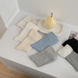 Gros plan de chaussettes en coton côtelé aux tons pastels sur un escalier blanc