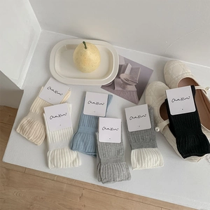 Gros plan de chaussettes en tricot côtelé aux tons pastel avec emballage de marque épuré