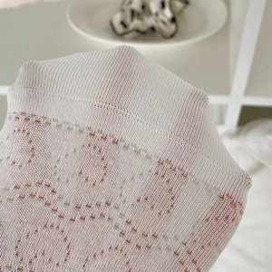 Détail de chaussettes résille blanches avec cœurs découpés et bordure en dentelle volantée