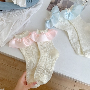 Detail of cream knit socks featuring lace ruffles and heart patterns in a flat lay view