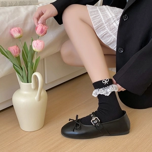 Detail of black Mary Jane shoes with lace trim socks and pearl bow accessories