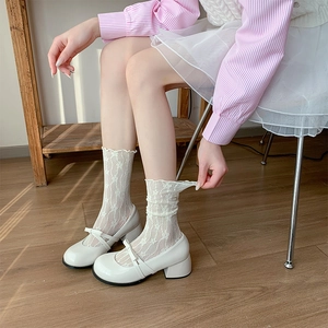 Close-up of white floral lace socks paired with Mary Jane bow shoes on wooden floor