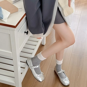 Détail de chaussures Mary Jane argentées avec nœud et chaussettes en maille grise