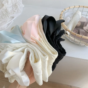 Close-up of knit crew socks featuring large satin bows in white, black, pink and blue
