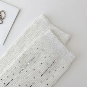 Detail of white ribbed knit socks with sparkling silver rhinestones and textured vertical stripes
