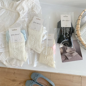 Detailed view of cream and black ruffle socks with heart jacquard in a zipper bag