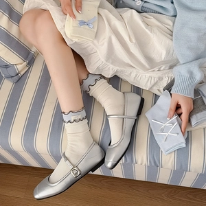 Close-up of silver Mary Jane shoes with metallic finish and white frilly socks
