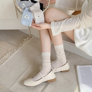 Detail of ribbed knit crew socks with a triangle patch worn with Mary Jane flats