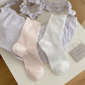Détail de chaussettes en résille rose et blanc avec bords volantés et motif ajouré