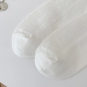 Detailed macro view of white cotton-blend socks showing vertical ribbing and cable knit texture
