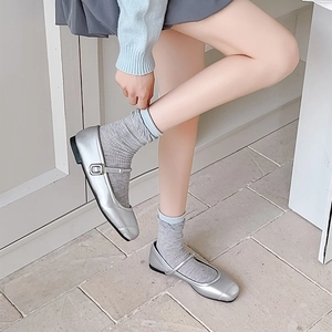 Close-up of silver Mary Jane flats with metallic finish and grey mid-calf socks