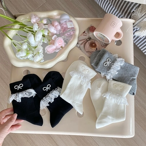 Detail of lace trim and pearl bow embellishments on three-color knit crew socks
