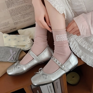 Detail of silver Mary Jane flats with bows and pink socks featuring delicate lace trim