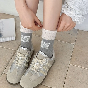 Grey mid-calf socks with white lace trim and lucky patch shown with sneakers