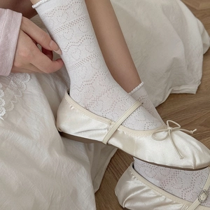 Détail de chaussettes blanches à motif cœur avec ballerines en satin à nœud