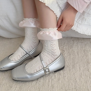 Detail of cream-colored socks with pink ruffles and heart pattern with silver shoes