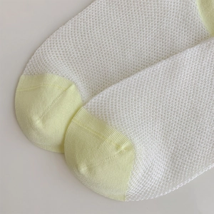 Close-up of white mesh knit socks with yellow toe detail and breathable hole structure
