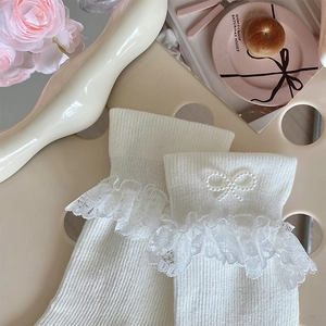 Close-up of white ribbed socks with lace trim and elegant pearl bow accents on a chair