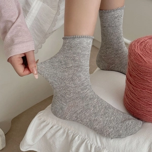 Détail de chaussettes grises extensibles avec bords à volants et maille texturée