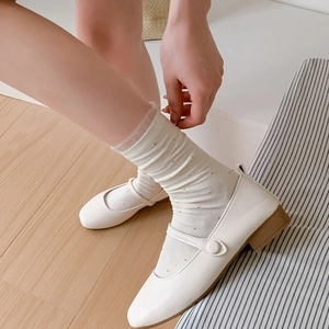Beige Mary Jane shoes with polka dot lace socks on a warm wooden background