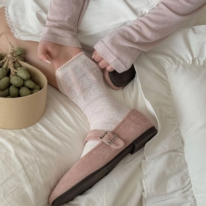 Gros plan de ballerines Mary Jane roses avec chaussettes en dentelle sur lit doux