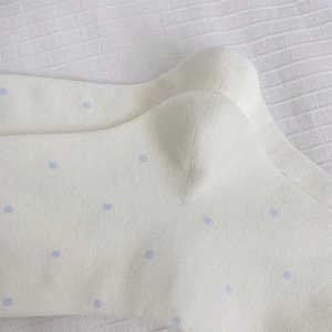 Detailed close-up of cream cotton socks featuring blue polka dots and fine ribbed texture
