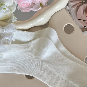 Detailed close-up of white ribbed knit socks with elegant lace trim and pearl bow accent
