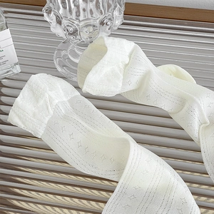 Nahaufnahme weißer Spitzensocken mit Stern-Netzmuster und elastischen Spitzenbündchen