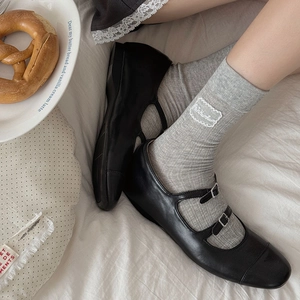 Gros plan de chaussettes grises à côtes avec dentelle blanche et chaussures Mary Jane