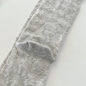 Macro shot of knitted white lace socks with hollow bow patterns and ribbed texture