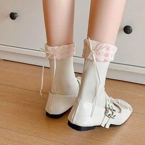 Gros plan sur des chaussettes blanches avec volants à carreaux roses et petits nœuds