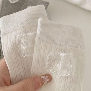Vue macro de chaussettes blanches à côtes avec bordure en dentelle et patch brodé