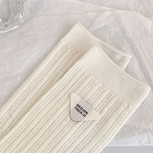 Detail of off-white ribbed socks featuring a unique triangle patch with black lettering