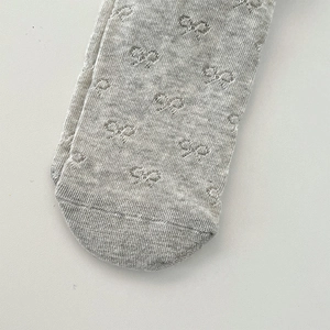Detailed macro view of gray knitted fabric with delicate bow pattern for baby tights