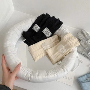 Detail of ribbed knit leg warmers in black, beige, grey, and blue with lucky label