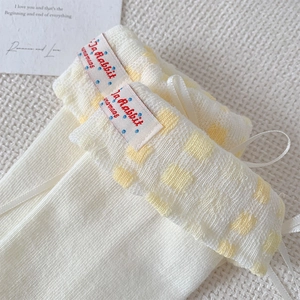 Gros plan de chaussettes en tricot crème avec revers à carreaux jaunes et nœud en soie