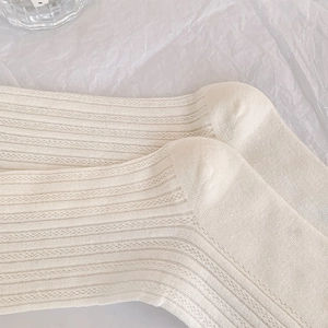Close-up of cream knit socks featuring vertical ribs and breathable mesh texture
