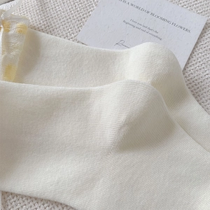 Détail de chaussettes en tricot crème à pois jaunes avec une texture douce et côtelée