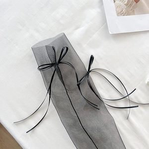 Detailansicht von transparenten schwarzen Netzsocken mit eleganten Bandschleifen