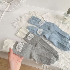 Detailed close-up of blue and grey ribbed socks with lucky embroidery and lace trim labels