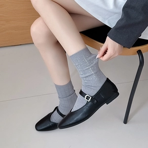 Close-up of grey crew socks with sparkling rhinestones worn with black Mary Jane shoes