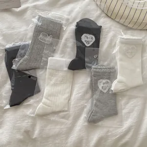 Détail de volants en dentelle et broderie cœur sur chaussettes côtelées en trois couleurs