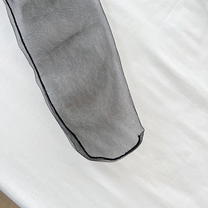 Nahaufnahme schwarzer transparenter Netzsocken mit Schleifendetail und Overlock-Naht