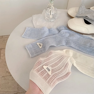 Detailed knit texture and triangle logo tag on light gray and off-white cotton crew socks