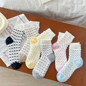 Detail of hollow mesh socks with ruffled cuffs and button accents in six pastel colors