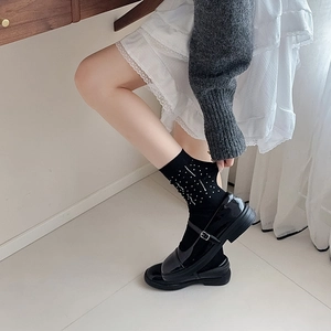 Close-up of black rhinestone crew socks styled with glossy Mary Jane buckled shoes