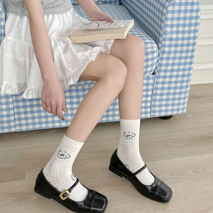 Close-up of white crew socks with cartoon dog jacquard and black Mary Jane shoes